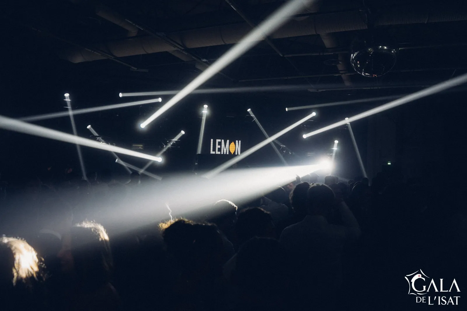 Jeux de lumière et public lors d’un gala, le logo LEMON projeté derrière la cabine DJ.