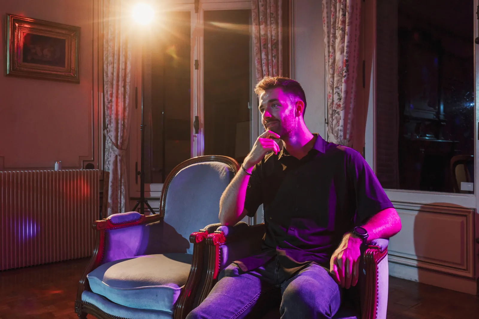 Thomas Scholtes, alias DJAY LEMON, dans un fauteuil sous un éclairage magenta pendant une soirée.